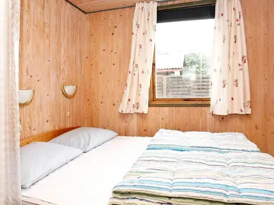 a bed in a wooden room with a window at 6 person holiday home in Løkken-By Traum in Løkken