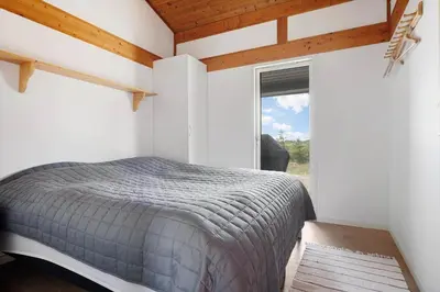 a bedroom with a bed and a large window at LK2113-Lokken-Kettrup-Bjerge-vej-67 in Løkken