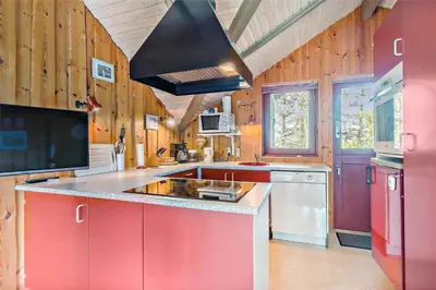 a large kitchen with red cabinets and a black hood at LK473-Lokken-Kettrup-Bjerge-Vej-47 in Løkken
