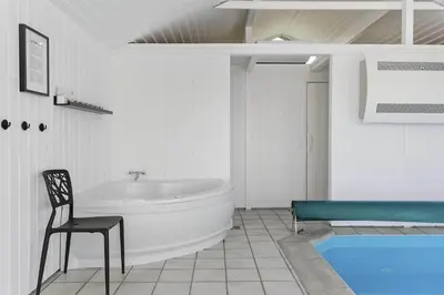 a bathroom with a tub and a chair next to a bath tub at LK1001-Lokken-Nellysvej-21 in Løkken
