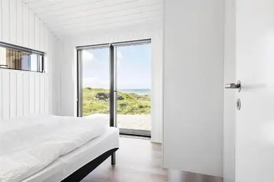 a bedroom with a bed and a view of the ocean at LK1240-Lokken-Rosavej-13 in Løkken