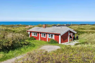 a red house on a hill with the ocean in the background at LK1427-Lokken-Nannasvej-26 in Løkken