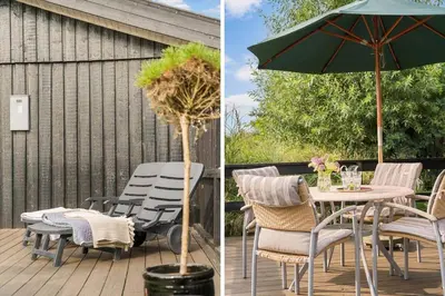 a table and chairs and an umbrella on a deck at LK2098-Lokken-Magdalenevej-51 in Løkken