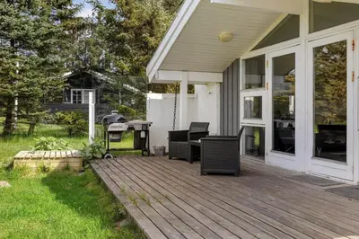 a wooden deck with chairs and a grill on a house at LK1892-Lokken-Marthinesvej-37 in Løkken