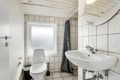 a bathroom with a sink and a toilet and a window at LK1892-Lokken-Marthinesvej-37 in Løkken