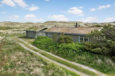 a house in a field with a dirt road at LK539-Lokken-Sylviavej-27 in Løkken