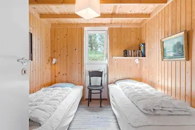 a bedroom with two beds and a chair in it at LK1054-Lokken-Lottesvej-22 in Løkken