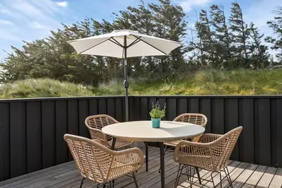 a table and chairs with an umbrella on a deck at LK1054-Lokken-Lottesvej-22 in Løkken