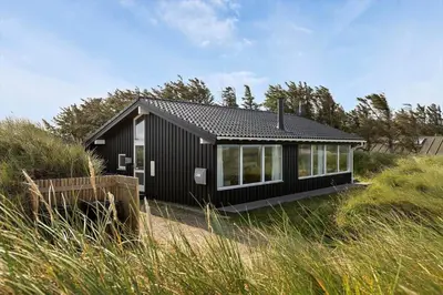 a black house in a field of tall grass at LK1054-Lokken-Lottesvej-22 in Løkken