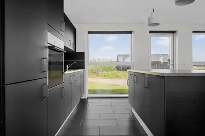 a kitchen with black cabinets and a large window at LK1979-Lokken-Kringelbaekvej-42 in Løkken