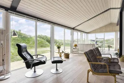 a living room with chairs and a lot of windows at LK157-Lokken-Ruthsvej-15 in Løkken