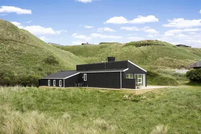 a black house on top of a grassy hill at LK157-Lokken-Ruthsvej-15 in Løkken