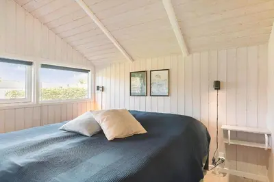 a bedroom with a bed in a room with two windows at LK1804-Lokken-Kristavej-43 in Løkken