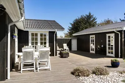 a deck with chairs and a table and a building at LK344-Lokken-Ragnhildsvej-3 in Løkken