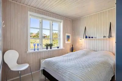 a bedroom with a bed and a chair and a window at LK344-Lokken-Ragnhildsvej-3 in Løkken