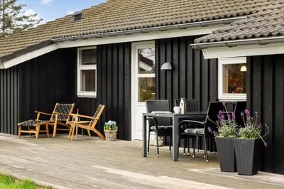 a black house with a table and chairs on a deck at LK1325-Lokken-Karinavej-59 in Løkken