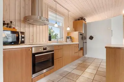 a kitchen with wooden cabinets and a sink and a refrigerator at LK1325-Lokken-Karinavej-59 in Løkken