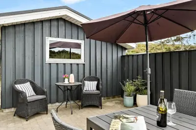 a patio with a table and chairs and an umbrella at LK1786-Lokken-Nannasvej-18 in Løkken