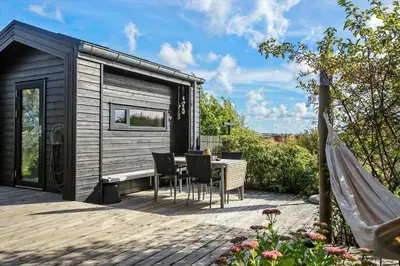 a tiny house with a table and chairs on a deck at LK1946-Lokken-Kringelbaekvej-5 in Løkken