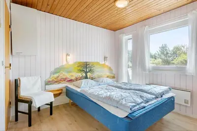 a bedroom with a bed and a chair and a window at LK561-Lokken-Lisbethsvej-1 in Løkken