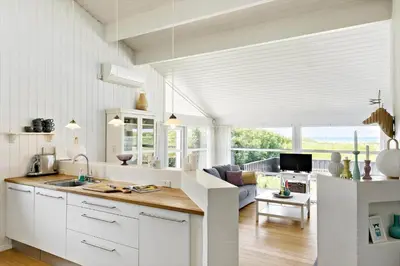 a kitchen with white cabinets and a living room at LK1790-Lokken-Gronhoj-Strandvej-174 in Løkken