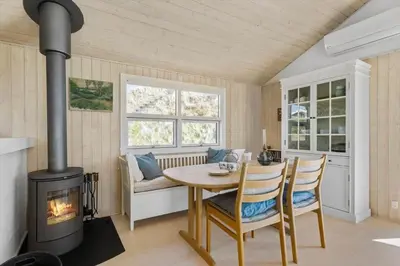 a dining room with a wood stove and a table at LK1985-Lokken-Monasvej-24 in Løkken