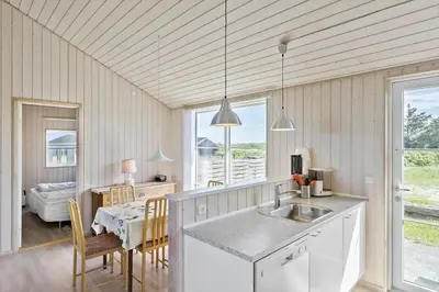 a kitchen with a sink and a table with chairs at LK528-Lokken-Rosavej-5 in Løkken