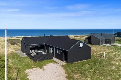 a black house on the beach near the ocean at LK1463-Lokken-Rosavej-11 in Løkken