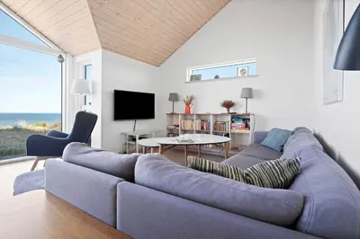 a living room with a couch and a table and a tv at LK1463-Lokken-Rosavej-11 in Løkken