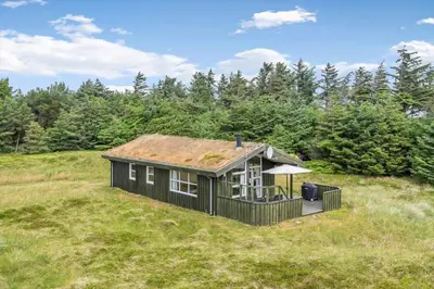 a house on a grassy hill with trees at LK248-Lokken-Sinnesvej-43 in Løkken