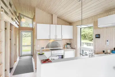 a kitchen with white appliances and wooden walls at LK248-Lokken-Sinnesvej-43 in Løkken