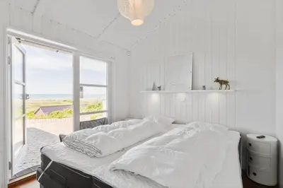 a white bedroom with a bed and a large window at LK329-Lokken-Marensvej-12 in Løkken