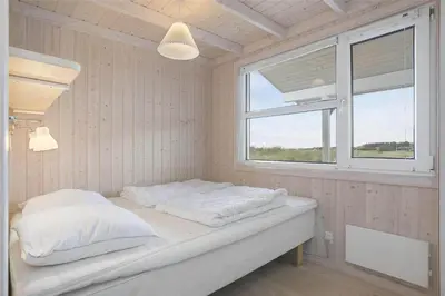 a bedroom with a bed with white sheets and a window at LK1179-Lokken-Normasvej-6 in Løkken