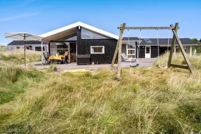 a black house on the beach with a swing at LK2065-Lokken-Rikkesvej-5 in Løkken