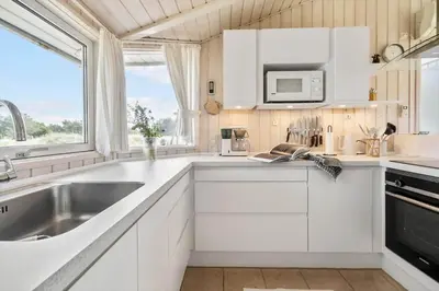 a white kitchen with a sink and a microwave at LK2065-Lokken-Rikkesvej-5 in Løkken