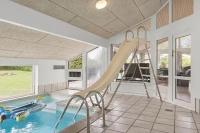 a indoor swimming pool with a slide in a house at LK2084-Lokken-Margrethevej-76 in Løkken