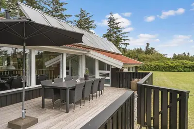 a deck with an umbrella and a table and chairs at LK2084-Lokken-Margrethevej-76 in Løkken