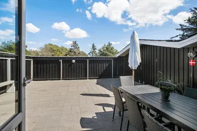 a patio with a wooden table and an umbrella at LK1779-Lokken-Lydiavej-2 in Løkken