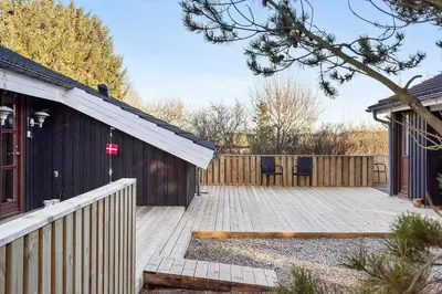 a wooden deck with two chairs and a house at LK933-Lokken-Olgavej-34 in Løkken