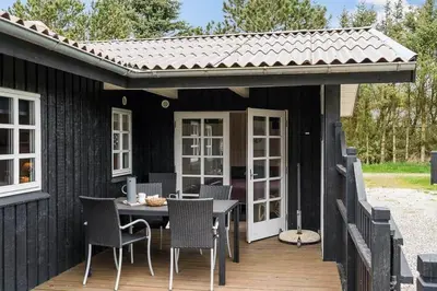 a black house with a table and chairs on a deck at LK2029-Lokken-Magdalenevej-55 in Løkken