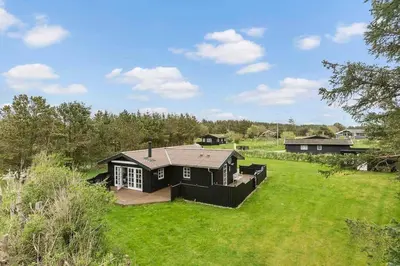 a black house in a field of green grass at LK2029-Lokken-Magdalenevej-55 in Løkken