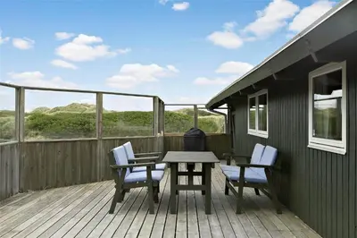 a wooden deck with a table and chairs on it at LK1709-Lokken-Ruthsvej-12 in Løkken