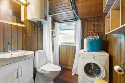 a bathroom with a toilet a sink and a washing machine at LK1709-Lokken-Ruthsvej-12 in Løkken
