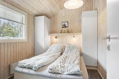 a bed in a room with wooden walls and a window at LK1221-Lokken-Louisevej-5 in Løkken