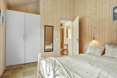 a bedroom with a white bed and wooden walls at BL1220-Blokhus-Peter-Andersensvej-21 in Blokhus