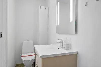 a white bathroom with a toilet and a sink at BL1583-Blokhus-Strandvejen-14-Lejl-12 in Blokhus
