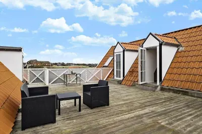 a balcony with chairs and tables on a roof at BL1583-Blokhus-Strandvejen-14-Lejl-12 in Blokhus