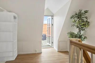 a hallway with white walls and a staircase with a plant at BL1583-Blokhus-Strandvejen-14-Lejl-12 in Blokhus