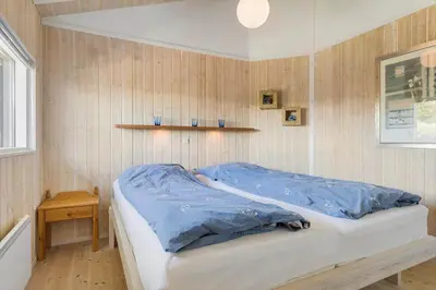 a bedroom with a bed with blue sheets on it at BL1201-Blokhus-Stromsvej-1 in Blokhus