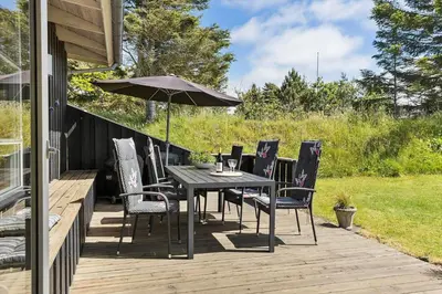 a table and chairs with an umbrella on a deck at BL1201-Blokhus-Stromsvej-1 in Blokhus